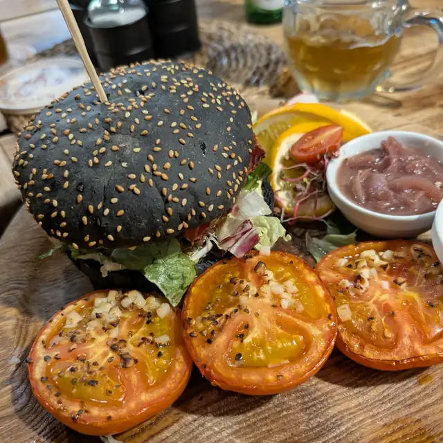 Burger w czarnej bułce z pieczonymi pomidorami i sosem