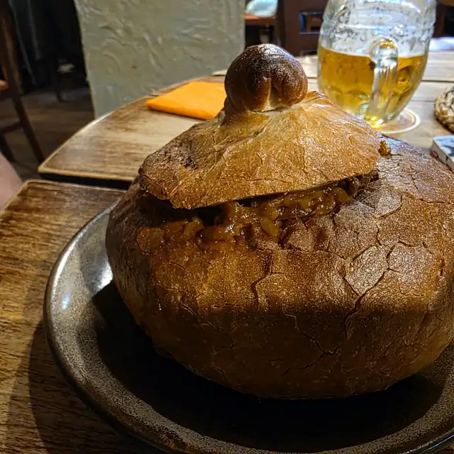 Zupa zapiekana w okrągłym bochenku chleba z chlebową pokrywką