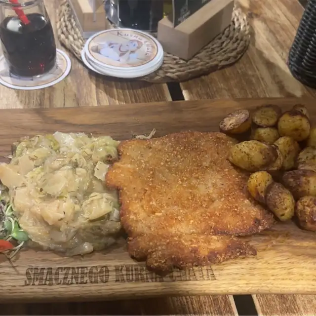 Kotlet w orzechowej panierce z ziemniakami opiekanymi i kapustą na desce