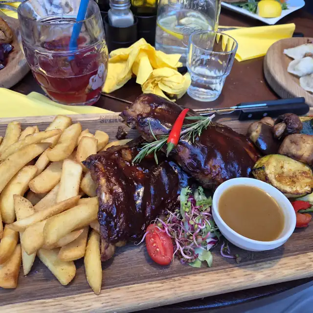 Żeberka BBQ z frytkami, grillowanymi warzywami i sosem na długiej desce